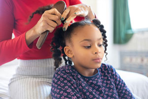child receiving hair relaxer treatment